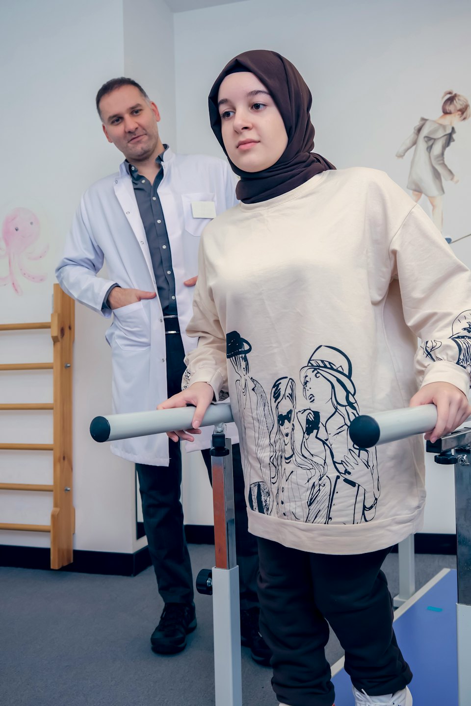 Woman uses parallel bars during physical therapy with therapist observing.