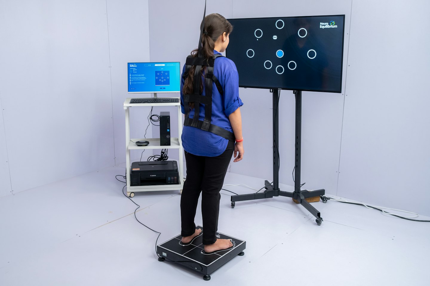 Woman on force plate during balance test with monitor display.